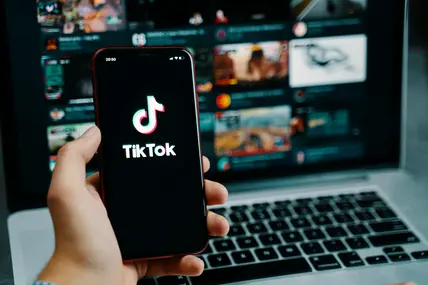 Hand mit Handy auf dem TikTok geladen wird. 